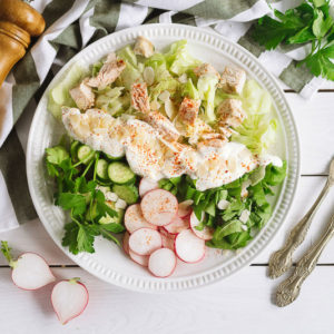 Салат айсберг, курицей и овощами | Iceberg salad with square slices of chicken fillet, chopped cucumber, parsley, radish, sour cream and sprinkled with blanched peanut slices. Wooden pepper mill.